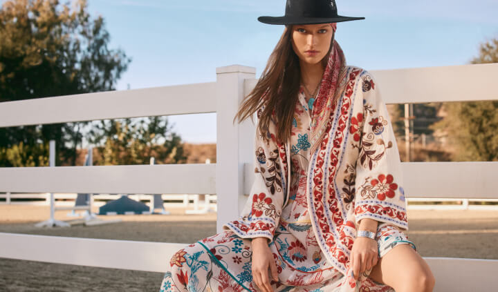 Model sitting wearing an embroidered kimono with dress